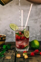 Summer mojito cocktail with raspberries, mint and lime on wooden background