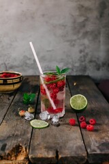 Summer mojito cocktail with raspberries, mint and lime on wooden background