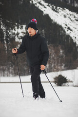 man in winter clothes climbs the ski slope to the top with the help of climbing poles for better stability and easier climbing to the mountains. Focused expression. Lifestyle change. Fresh air