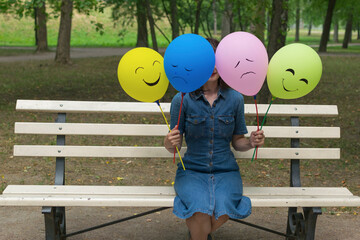 Woman holding air balloons with funny drawn faces.