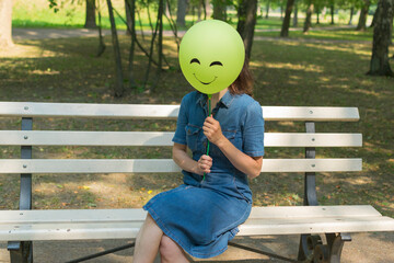 Woman holding air balloon with funny drawn face.