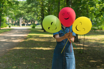 Woman holding air balloons with funny drawn faces.
