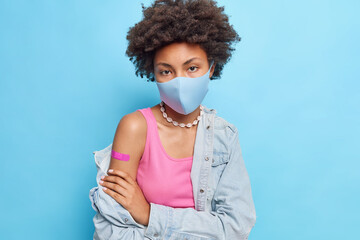 Sad and serious dark skinned woman feels tired after a long visit to the clinic in a mask, holds...