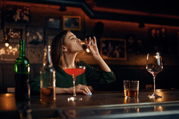 Stressed woman drinks alcohol at counter in bar