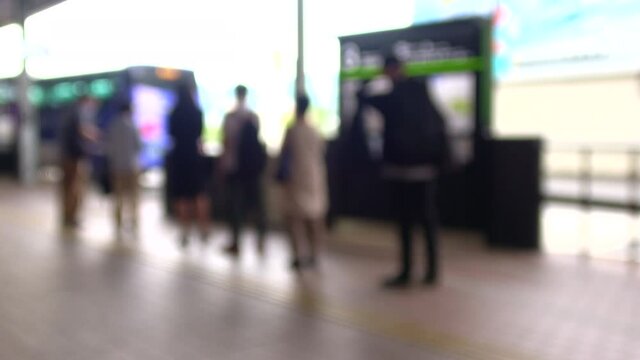 Blurred people with mask practicing social distancing waiting for bus in line at bus station in Hiroshima city, Japan. 4K. Defocus shot. July 6, 2021