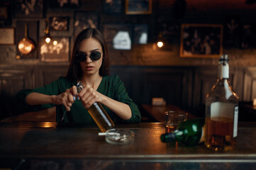 Woman opens bottle of beer at the counter in bar