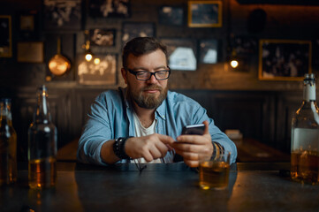 Man with mobile phone sitting at counter in bar