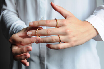 Close up on a person putting on gold rings on the fingers
