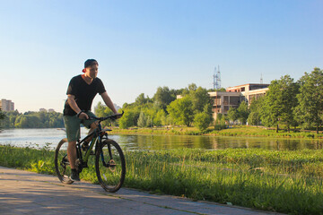 Fototapeta na wymiar A guy rides a bike in the park. Young fit man during a bike ride on a sunny day