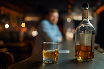 Bottle of alcohol and glass on counter in bar