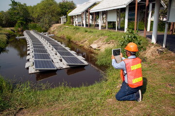 An Asian Engineers investigating floating solar panels Renewable Solar Power Plant.
