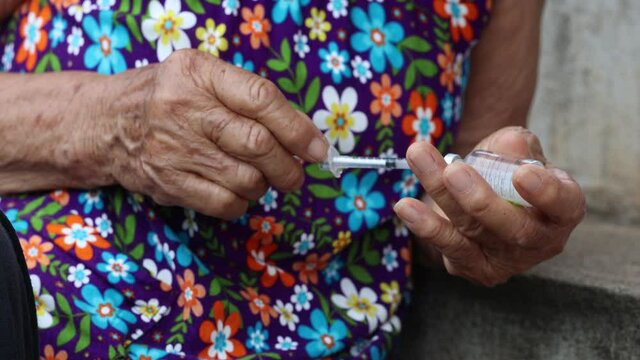 Close-up of a Senior woman giving herself an injection. Drug treatment, Congenital disease, Health care.