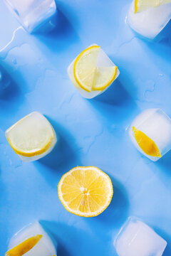 Modern geometric composition of the frozen slices of lemon and ice cubes on a blue background