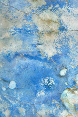 Wall with the blue whitewash falling off fragment with cracks as a background texture. Old paint on the wall with old plaster, Abstract texture in blue color