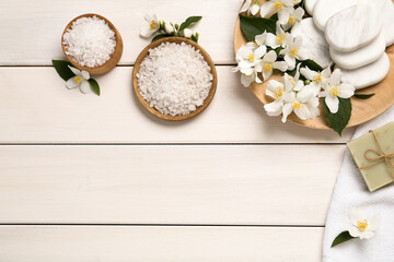 Flat lay composition with spa stones and beautiful jasmine flowers on white wooden table, space for text