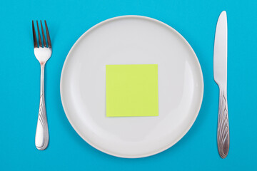 Colored Sticky Note or Memo Paper on White Ceramic Plate Lying On Blue Background - Top View, Flat Lay