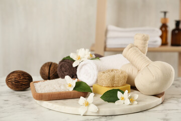 Composition with beautiful jasmine flowers and sea salt on white marble table indoors