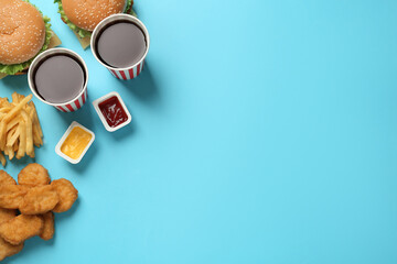 Flat lay composition with delicious fast food menu on light blue background. Space for text