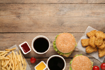 Flat lay composition with delicious fast food menu on wooden table. Space for text