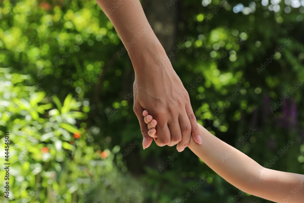 Wall mural Mom and her child holding hands in park, closeup