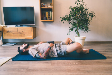 Side view Man doing yoga on the floor practicing Wind Relieving pose
