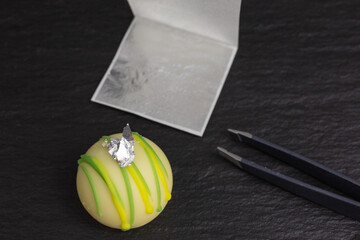 piece of edible silver leaf on chocolate truffle with tweezers