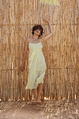 Portrait of a young woman in front of a cane wall.