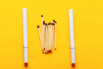 Wooden matches and cigarettes with filter . yellow background