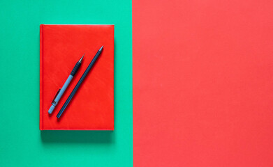 Back to school concept. Red notepad with pencils. Green and red background. Flat lay with copy space.