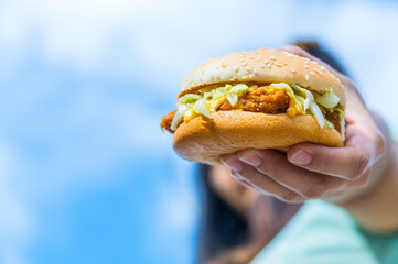 close up of tasty burger. woman hand holding juicy hamburger. concept hamburger at street food festival. summertime. summer vacation picnic. space for text