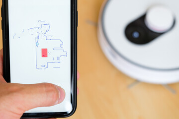 Close up a mobile phone application for managing of robot vacuum cleaner in mans hand. Smart technology for housekeeping 