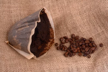 Raamstickers Marc de café usagé dans un filtre en papier à côté de grains de café en gros plan sur fond de toile de jute © Richard Villalon