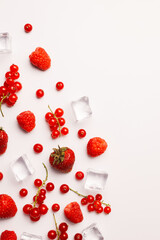 Pattern with assorted red berries and ice cubes isolated on a bright white background. Creative healthy fruit food concept with copy space. Flat lay, top view.