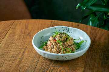 Rice wok with vegetables and chicken in a plate on a wooden background. Asian cuisine