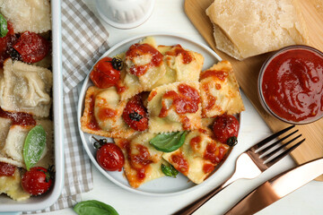 Tasty ravioli with tomato sauce served on white table, flat lay