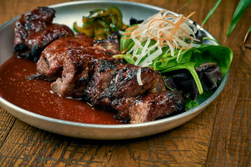Grilled beef or pork with white barbecue sauce ponzu cucumbers and sauce in a plate on a wooden background