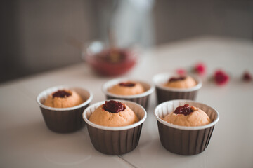 Tasty cupcakes with strawberry jam filling stay on kitchen table close up. Preparation for birthday party or wedding day. Breakfast time.
