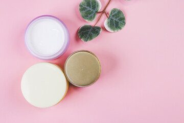 Obraz na płótnie Canvas Mockup cosmetic jar with cream or lotion and leaf isolated on pink background, mock up package for advertising, skincare or cosmetology, top view, flat lay, skin care and treatment with product.