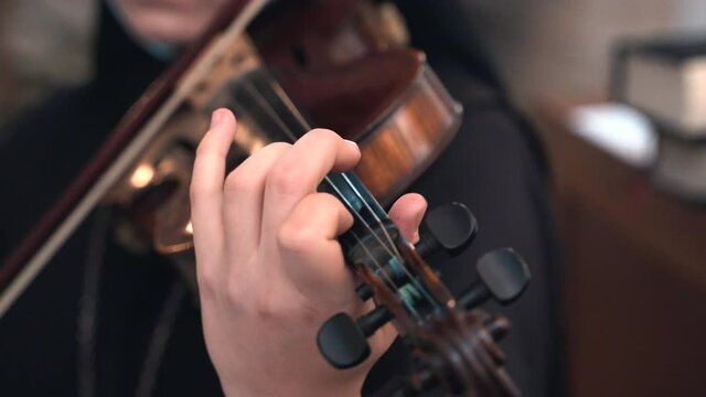 Close-up details shot of nun's hands playing the violin in church during traditional religious ceremony, nun with professional musician skills performing glorifying songs on church mass. Musical