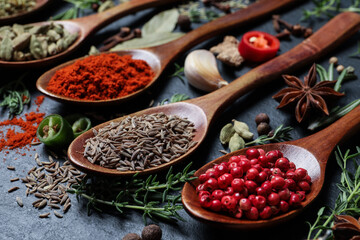 Different natural spices and herbs on black table, closeup