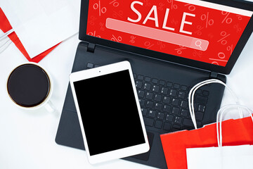 tablet, laptop, coffee and shopping bags on a light background. online shopping concept