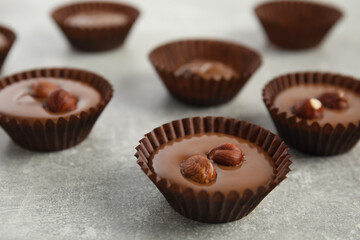 Delicious chocolate candies with hazelnuts on grey table, closeup