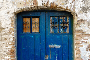 Old blue old wooden door with mailbox in a brick wall