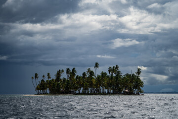 Small tropical island with coconut palm trees during stormy, cloudy weathre. Adventure and travel concept 
