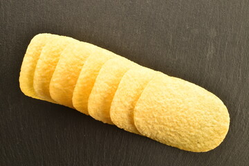 Several potato chips on a serving slate board, close-up, top view.