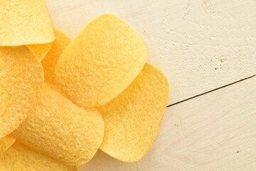 Several potato chips on a wooden table, close-up, top view.