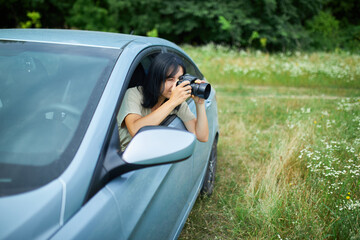 Woman photographer sitting in the car and photographing a flower field landscape