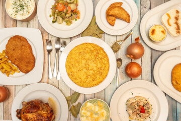 set of simple dishes of Spanish food. Roast chicken, stuffed cannelloni, Russian salad with belly, Spanish omelette, Milanese with potatoes, empanadas, potatoes aioli