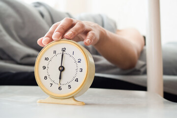 A woman's hand presses the alarm button in the morning. Young woman reach out one's hand Press the button to turn off the alarm clock in morning