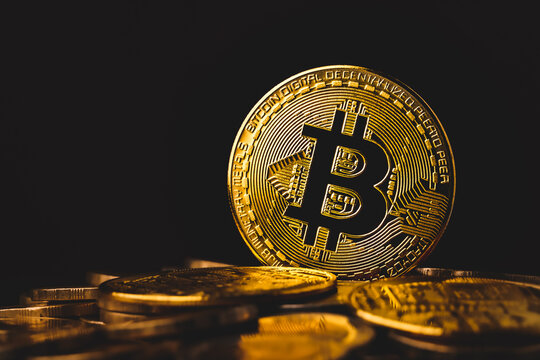 Selective focus of golden bitcoins on dark background with a pile of gold coins. concept of  investing in cryptocurrency.
